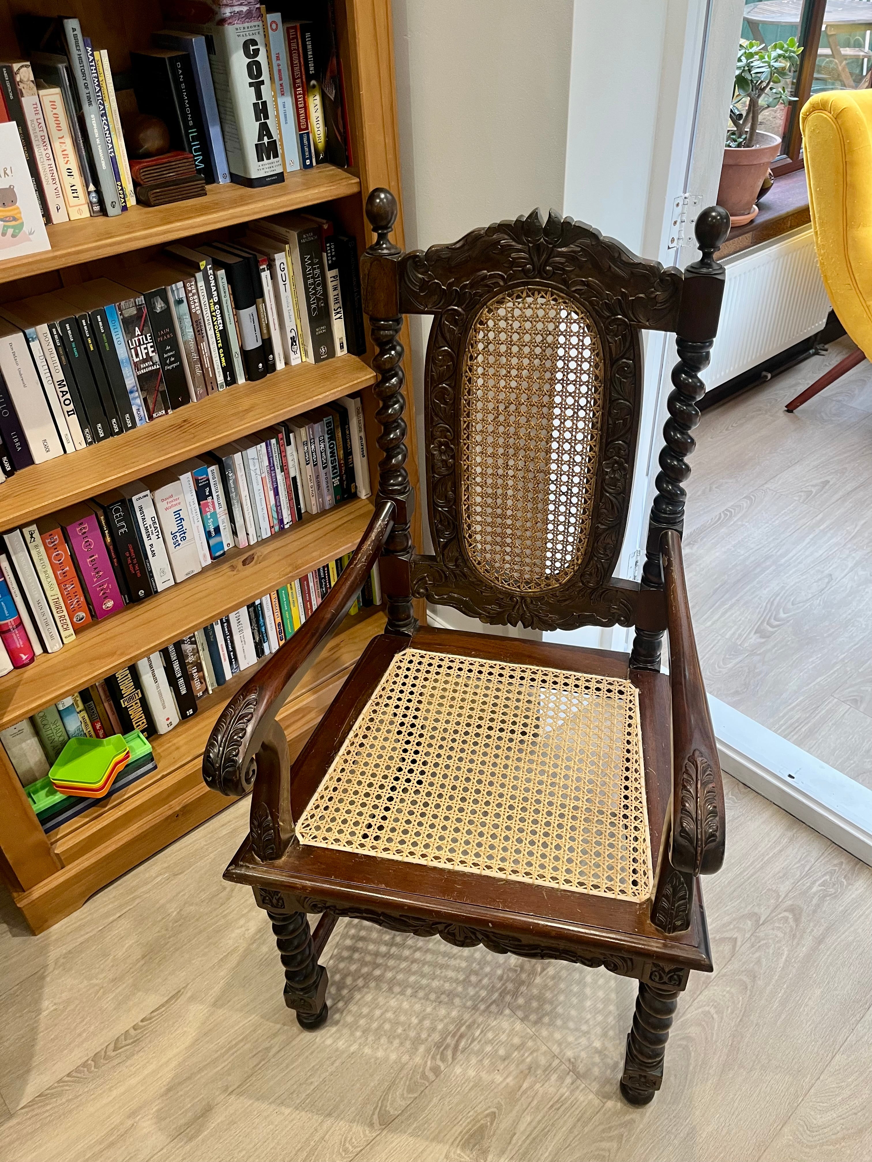 Chair with restored cane seating next to a bookshelf and conservatory